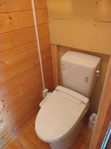 a bathroom with a white toilet in a wooden wall at 星逢える宿ー森のコテージ気仙沼 in Kesennuma