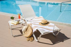 einen Stuhl mit Handtuch und Hut neben einem Pool in der Unterkunft Hotel Triton Beach in Cala Ratjada