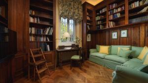 a living room with a green couch and book shelves at VILLA GAIUS 8&2, Emma Villas in Rosignano Marittimo
