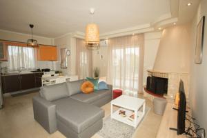 salon z szarą kanapą i kuchnią w obiekcie Medea's Luxury Apartment w mieście Perea