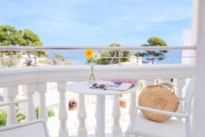 einen Tisch und Stühle auf einem Balkon mit Meerblick in der Unterkunft Hotel Triton Beach in Cala Ratjada