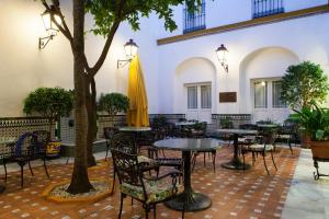 a restaurant with tables and chairs and a tree at Hotel Cervantes in Seville