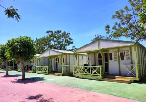 uma fila de casas modulares verdes com uma árvore em Camping El Jardín em El Campello