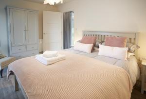 um quarto com uma cama grande com almofadas cor-de-rosa e brancas em Mallow Lodge 6 em Bamburgh