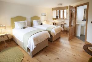 a bedroom with two beds and a bathroom with a sink at The Longbarn at Caerfallen in Ruthin