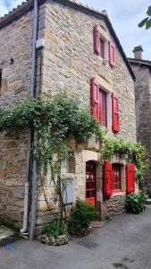 an old stone building with red shutters and plants at La Garance Voyageuse in Boyne