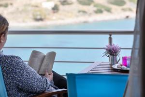 Eine Frau, die an einem Tisch sitzt und ein Buch liest. in der Unterkunft Serenity apartment Mochlos in Mochlos