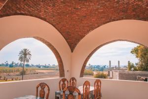 a dining room with two arched windows and a table and chairs at Tasneem Palace in Luxor