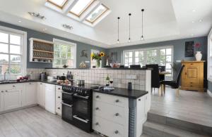 a kitchen with white cabinets and a black counter top at Broad Meadows Farmhouse 12 Guests in Bayton