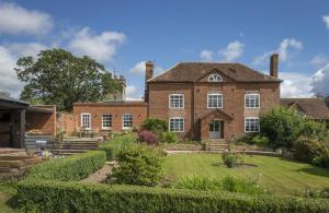 a large brick house with a garden in front of it at Broad Meadows Farmhouse 12 Guests in Bayton