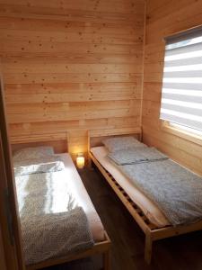 two beds in a log cabin with a window at Domki Letniskowe U Żuni in Chłopy