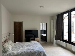 a white bedroom with a bed and a television at Suites Number 22 Antwerp in Antwerp