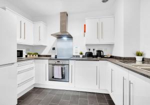 a white kitchen with white cabinets and a stove at Station Walk By My Getaways in Brighton & Hove