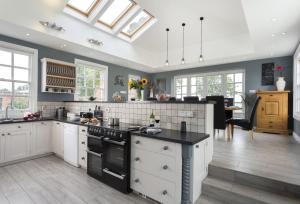 a kitchen with white cabinets and a black counter top at Broad Meadows Farmhouse 8 Guests in Bayton