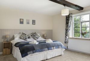 1 dormitorio con 1 cama con manta azul y blanca en Broad Meadows Farmhouse 8 Guests en Bayton