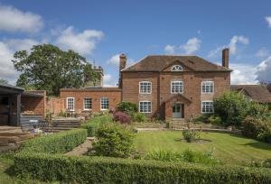 a large brick house with a garden in front of it at Broad Meadows Farmhouse 8 Guests in Bayton