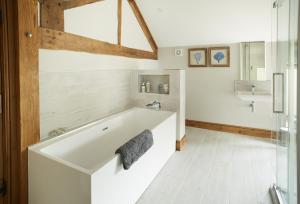 a bathroom with a bath tub and a sink at The Stone Barn in Downton