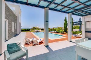 un patio con piscina, mesa y sillas en Seafront Villa Maya by Ruidoso Luxury, en Ayia Napa