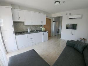 a kitchen with white cabinets and a couch in a room at Doğa Apart in Ortaca