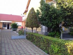 einen Backsteinsteg mit einer Hecke und Bäumen vor einem Gebäude in der Unterkunft Apartman Zanetti Ivica, Lipik 5 in Lipik