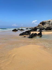 a sandy beach with rocks in the water at A deux pas de la grande plage in Quiberon