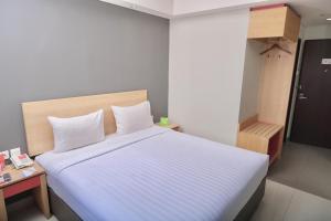 um quarto com uma cama grande e lençóis brancos em @Hom Semarang Simpang Lima em Semarang