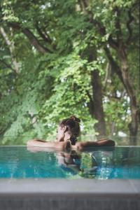 une femme posant sur une planche de surf dans une piscine dans l'établissement Shuum Boutique Wellness Hotel, à Kołobrzeg