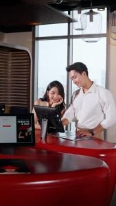 a man and a woman working at a counter at Wink Hotel Danang Centre - 24hrs stay in Da Nang