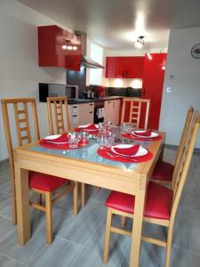 eine Küche mit einem Holztisch mit roten Schränken in der Unterkunft Les Coquelicots in Cormaranche-en-Bugey