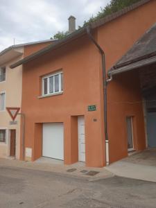 ein orangefarbenes Gebäude mit zwei weißen Garagentüren in der Unterkunft Les Coquelicots in Cormaranche-en-Bugey