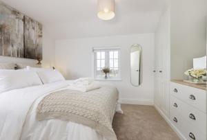 a white bedroom with a bed and a mirror at The Gap in Blockley