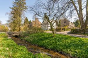 a stone bridge over a stream in front of a house at Linden Barn in Orton