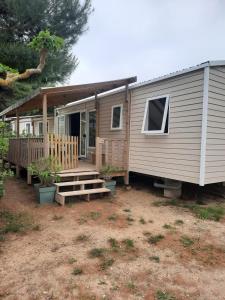 a tiny house with a porch and a deck at Charmant mobil-home 178 in Narbonne
