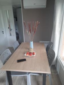 a dining room table with a vase and a plate of fruit at Charmant mobil-home 178 in Narbonne