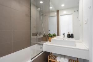 La salle de bains blanche est pourvue d'un lavabo et d'une douche. dans l'établissement Oceana Views, Cancelada, à Estepona