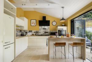 uma cozinha com paredes amarelas e um balcão com bancos em Rock Cottage em Minchinhampton