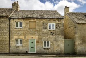 an old stone house with a green door at Rock Cottage in Minchinhampton