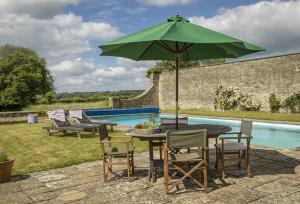 Long Barn في Coates: طاولة مع مظلة خضراء بجوار حمام سباحة