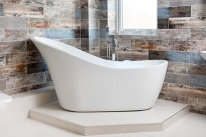 a white bath tub sitting on a counter in a bathroom at Stunning 1-Bed Cottage near Carlisle with Hot tub in Carlisle