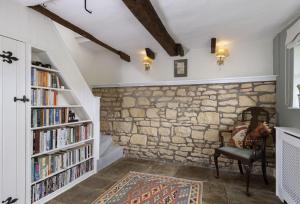 a room with a stone wall and book shelves with books at Southcroft Cottage in Bredon