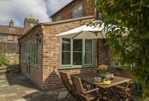 a patio with a table and an umbrella at Southcroft Cottage in Bredon