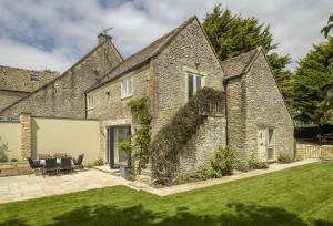 an external view of a stone house with a lawn at Cats Abbey Cottage in Northleach