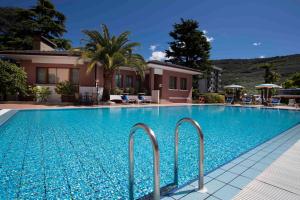 basen z niebieską wodą przed domem w obiekcie SunLake Hotel w mieście Riva del Garda