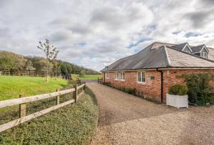 a brick building with a fence next to a field at Stables Cottage in Tilton