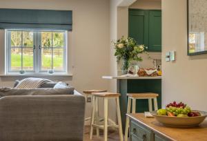 a kitchen with a couch and a bowl of fruit on a table at Stables Cottage in Tilton