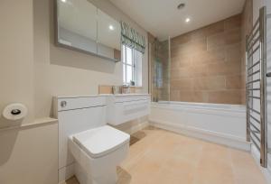 a bathroom with a toilet and a sink and a tub at Stables Cottage in Tilton