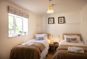 a bedroom with two beds and a window and a chandelier at Missy's House in the Woods in Harringworth