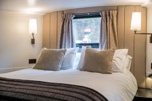 ALTIDO Elegant houseboat near Canary Wharf في لندن: غرفة نوم بسرير ومخدات بيضاء ونافذة