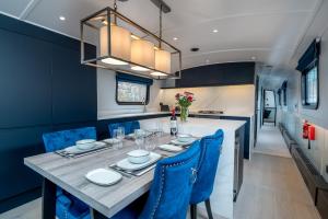 ein Esszimmer mit einem Tisch und blauen Stühlen in der Unterkunft JOIVY Elegant houseboat near Canary Wharf in London