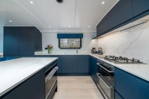 une cuisine avec des armoires bleues et des comptoirs blancs dans l'établissement ALTIDO Elegant houseboat near Canary Wharf, à Londres